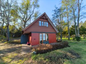 a small red house in a field with trees at Cabañas y Domos Calafquen in Coñaripe