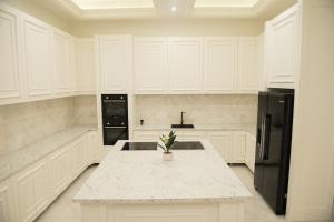 Una cocina con gabinetes blancos y un refrigerador negro. en Villa White, en Belgrado