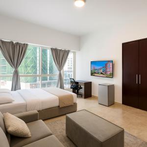 a bedroom with two beds and a desk and a tv at Marina Comfort Room with Bath inside in Dubai