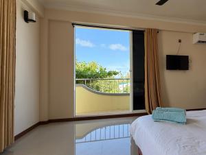 a bedroom with a window with a view of a balcony at Noah Private Beach House in Himmafushi