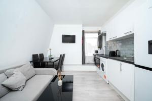a white living room with a couch and a kitchen at Strand Central Apartments 4th Floor in London