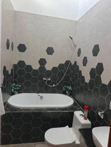a bathroom with a tub and a toilet and a sink at Cozy and Serene in Lusaka