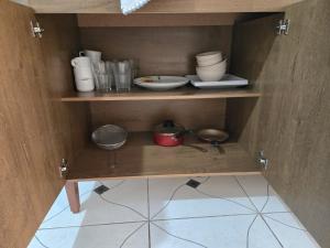 a wooden cabinet with bowls and dishes on it at Residencial Lima - Quarto 04 in São Luís