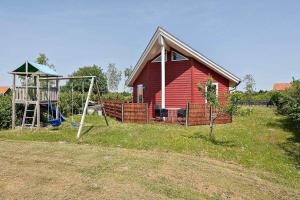 a red house with a playground and a swing at M12008-Vaeggerlose-Marielyst-Strandpark-112 in Marielyst