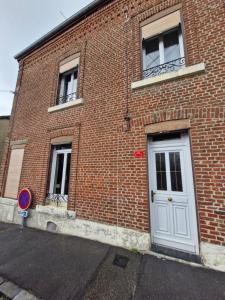 a brick building with a white door and two windows at La maison de Victoire in Fourmies