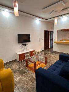 ein Wohnzimmer mit einer Couch, einem Tisch und einem Fernseher in der Unterkunft Résidence EDEN in Abidjan