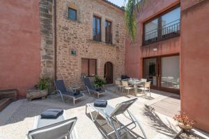 eine Außenterrasse mit Stühlen und Tischen und ein Backsteingebäude in der Unterkunft Casa Murallas para 6 con piscina en Alcudia cerca de playas in Alcúdia
