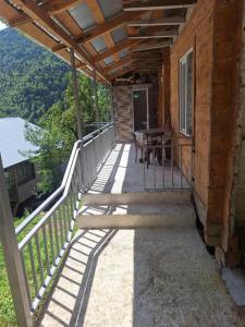 a porch of a cabin with a table and chairs at საოჯახო სასტუმრო,,ოდა ხიხანთან'' 