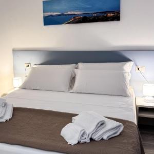 a bedroom with a bed with white sheets and pillows at Hotel Montenuovo 44 in Pozzuoli
