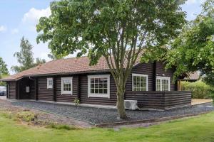 a log cabin with a tree in front of it at M212-Vaeggerlose-Marielyst-Strandpark-127 in Marielyst