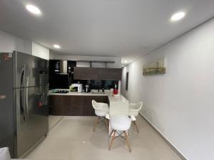 cocina con sillas blancas, mesa y nevera en Apartamento Ideal y Tranquilo, en Sabaneta