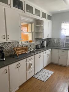 a kitchen with white cabinets and a wooden floor at DOWN TOWN BUNGALOW Entire home available in Farmington