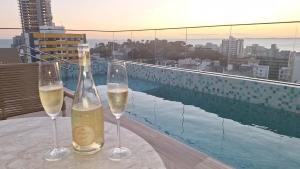 two glasses of wine sitting on a table next to a pool at Aconchegante apartamento studio na Barra in Salvador