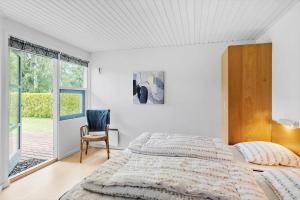 a bedroom with a bed and a chair and a window at M323-Vaeggerlose-Skovlystvej-38 in Bøtø By