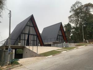 a building with two peaked roofs on a street at Chale cabana 2 linda vista na serra da Cantareira in Caieiras