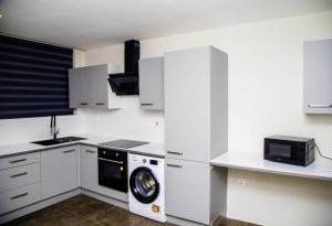 a white kitchen with a washing machine in it at Chris Resplendent Apartments in Accra +32 photos