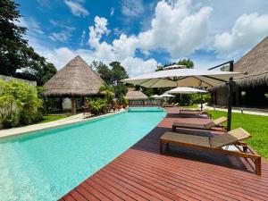 a swimming pool with chairs and an umbrella at Nalhá Hotel Boutique y Villas in Bacalar