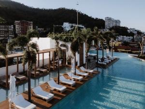 un hotel con piscina con tumbonas y palmeras en Maxwell Collection Romantic Zone, en Puerto Vallarta