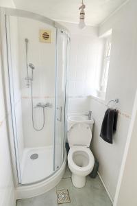 a white bathroom with a shower and a toilet at Xtra Large 4 Bedroom House, near Excel, London City and 5 walk to Train Station in London +17 photos