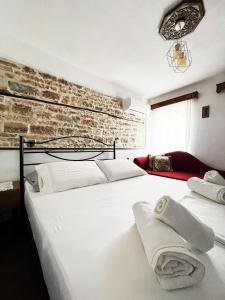 a bedroom with a large white bed with a brick wall at Castle Steps in Gjirokastër