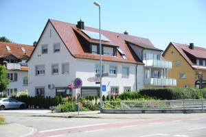 a white building with a red roof next to a street at Ferienzimmer Ellisee, kontaktloser Check-in in Friedrichshafen