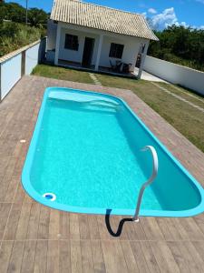 アハイアウ・ド・カボにあるCasa em Arraial do Cabo com Praia da Laguna dentro do Cond Recanto das Orquideasの家屋を背景にデッキ上のスイミングプール