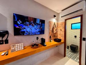 una televisione sul muro di un bagno con un bancone di Casinhas do Morro a Morro de São Paulo