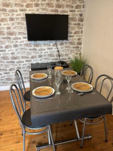 tavolo da pranzo con sedie e televisore su un muro di mattoni di Le Char'Mans, cocon suréquipé en centre ville a Le Mans