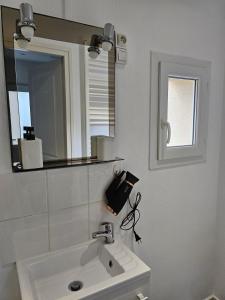 a white bathroom with a sink and a mirror at Studio calme à mantes la ville in Mantes-la-Ville