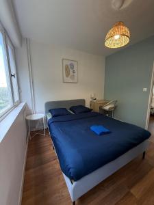 a bedroom with a bed with blue sheets and a table at Spacious 4 bedroom family home 5 min from Caen in Hérouville-Saint-Clair
