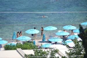 a group of people on a beach with blue umbrellas at Taormina Bay Lucia's House Roccalumera in Roccalumera