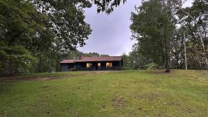 a house in the middle of a grassy field at Lake Russell Cabin Dog-Friendly, Secluded 4 Acres in Elberton