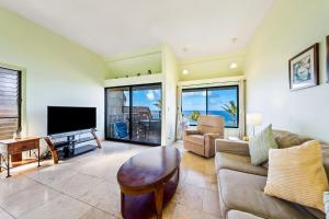 a living room with a couch and a television at Penthouse Condo with Panoramic Ocean Views in Princeville