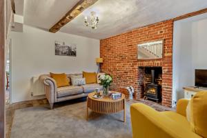a living room with a couch and a brick wall at Hawker Cottage in Lavenham