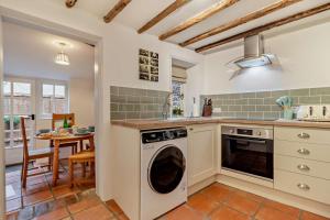 a kitchen with a washing machine and a dining room at Hawker Cottage in Lavenham