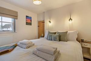 a bedroom with a large white bed with towels on it at Hawker Cottage in Lavenham