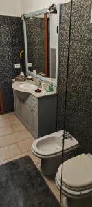 une salle de bain avec toilettes, lavabo et miroir dans l'établissement Quadrilocale con 2 bagni, à Castellanza