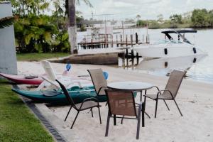 une table, des chaises et un bateau sur la plage dans l'établissement Vila das Carnaúbas | 2 chalés (Chalés Buriti e Atins), à Barreirinhas