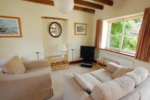 un salon avec deux canapés et une télévision dans l'établissement Church Barn Cottage, à Saxlingham 2 autres photos