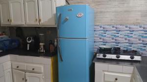 a blue refrigerator in a kitchen next to a stove at Recycled house in Santo Domingo