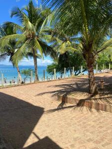 a sandy beach with two palm trees and the ocean at Casa em frente a praia - Ilha dos Frades in Salvador