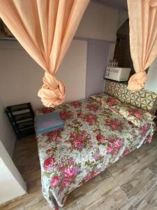 a bedroom with a bed with a floral bedspread at Casa em frente a praia - Ilha dos Frades in Salvador