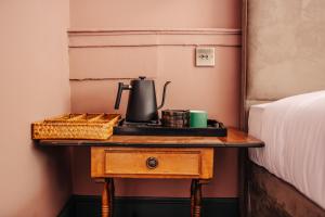 a table with a tea kettle on it next to a bed at Hermes Hotel by Nestor in Kingston upon Thames
