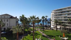 Studio Grand hôtel Croisette, by Welcome to Cannes في كان: اطلالة على حديقة فيها نخل ومبنى