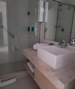 um banheiro com pia branca e espelho em Suíte em flat no Gonzaga Stay Helbor em Santos