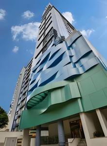 um edifício alto com uma fachada de vidro em Suíte em flat no Gonzaga Stay Helbor em Santos