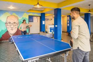 Dos hombres de pie frente a una mesa de ping pong en Shalom Backpackers Dharamkot McLeodganj, en McLeod Ganj