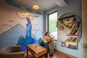 a woman sitting in a chair in a room with a mural at Shalom Backpackers Dharamkot McLeodganj in McLeod Ganj +12 photos