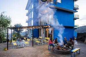 a group of people sitting around a fire pit in front of a building at Shalom Backpackers Dharamkot McLeodganj in McLeod Ganj