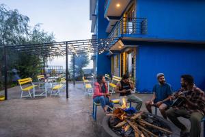 un grupo de personas sentadas alrededor de un fuego delante de un edificio en Shalom Backpackers Dharamkot McLeodganj, en McLeod Ganj